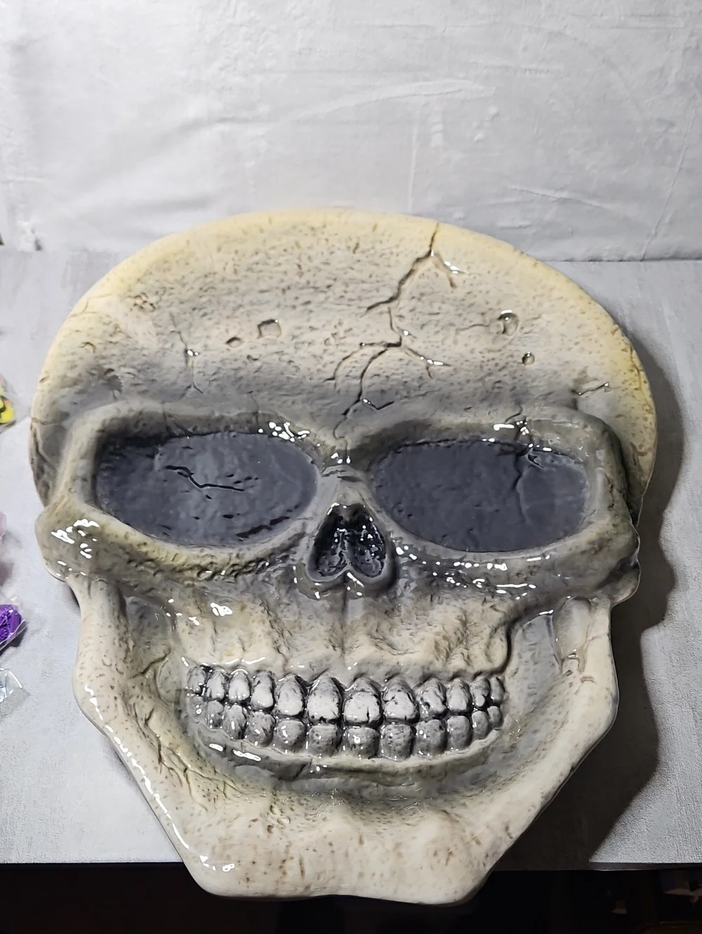 ceramic skull serving platter features a distressed, cracked gray finish